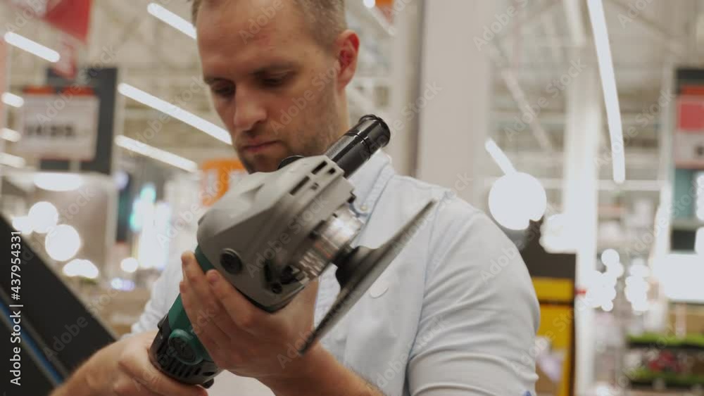 Adult man chooses a new angle grinder in a tool shop Adult man chooses a new angle grinder in a tool shop