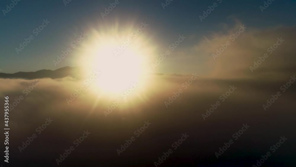 View of clouds over the mountains with the sun over the horizon during sunrise. Flyover through the Clouds Above Mountains at Sunset. Flying Over Fog at Sunrise. Fly from above fluffy clouds 4k View of clouds over the mountains with the sun over the horizon during sunrise. Flyover through the Clouds Above Mountains at Sunset. Flying Over Fog at Sunrise. Fly from above fluffy clouds 4k