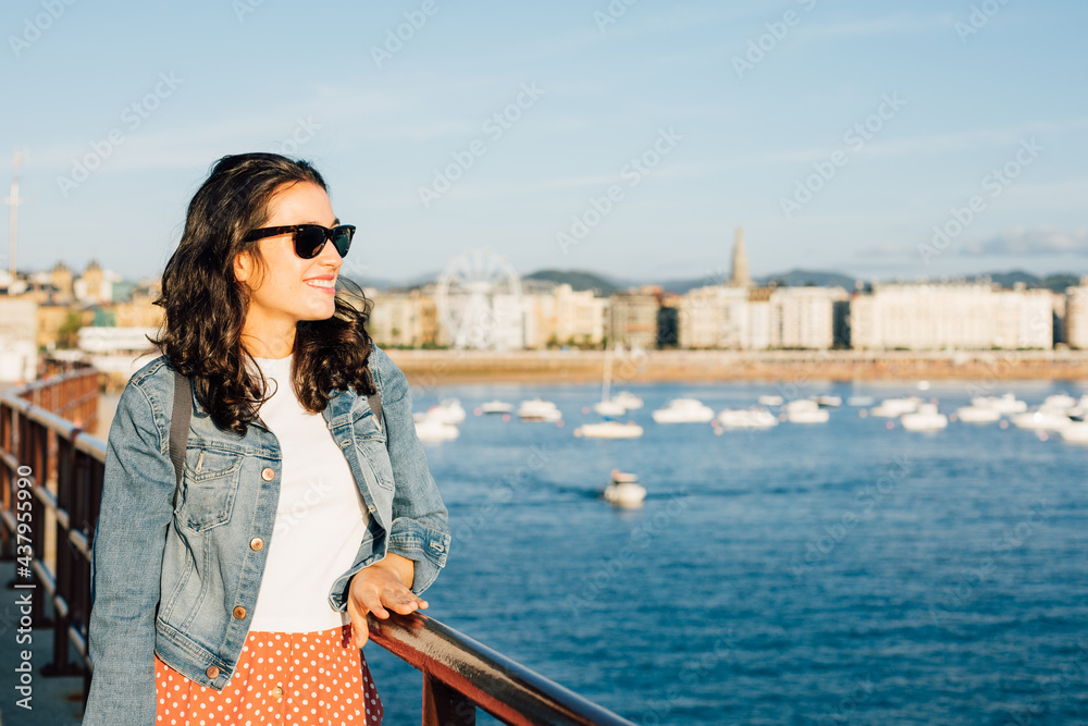 Happy young tourist woman enjoying the view of San Sebastian bay in Spain
