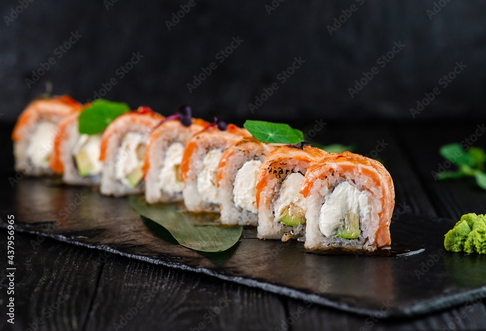 Japanese sushi roll on Black slate stone plate on wooden background. sushi pieces with Philadelphia cream cheese, avocado wrapped in rice with burned salmon Tataki fillet slices on top with greens
Japanese sushi roll on Black slate stone plate on wooden background. sushi pieces with Philadelphia cream cheese, avocado wrapped in rice with burned salmon Tataki fillet slices on top with greens