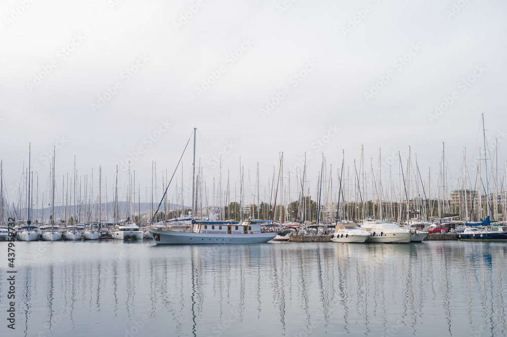 Fototapeta premium Yacht and boats parking in harbor. White sailing yachts at the pier. Sea yacht club. Aegean sea. Athens, Greece. Cloudy day.
