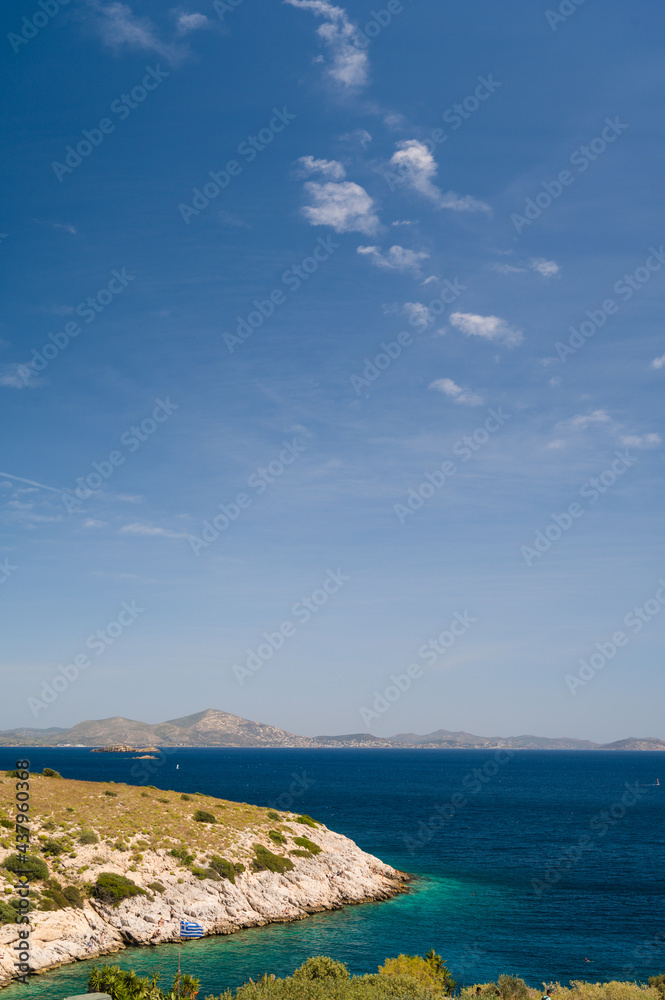Scenic landscape of Aegean sea at sunny summer day. Athens, Greece. Stone shore. Blue sky and water. Silhouette of mountains.