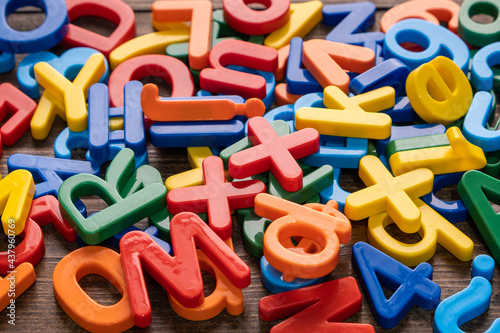 Top view of colorful plastic letters and numbers on wooden background