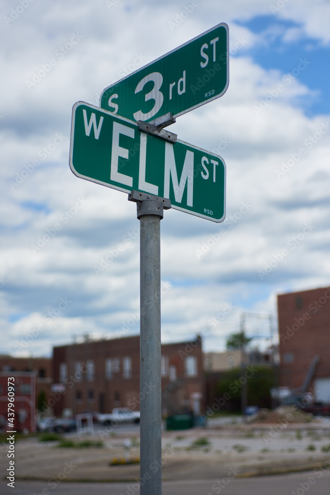 Street signs on the corner of 3rd and Elm with clouds and downtown buildings in the background. Street signs on the corner of 3rd and Elm with clouds and downtown buildings in the background.