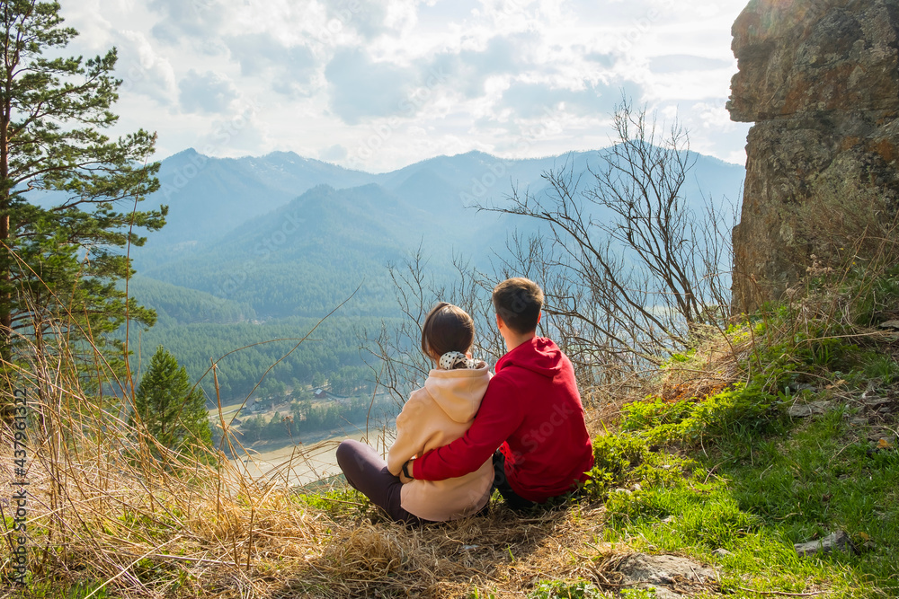 Young traveler couple resting and taking selfie in the mountains. Man and woman hiking with backpacks on a beautiful rocky trail. Family local travel and adventure concept