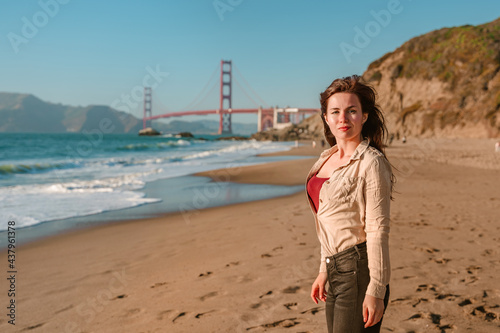 Photography Beautiful young woman with long hair walks on the beach overlooking the Golden G