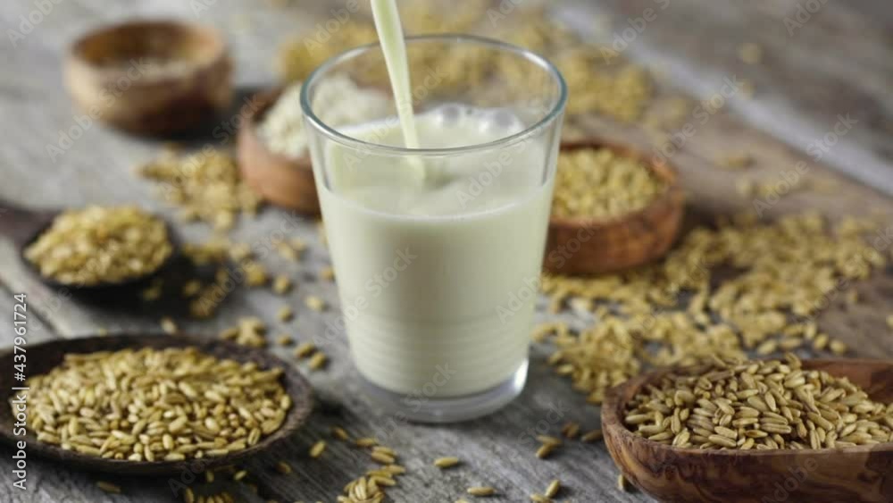Pouring a glass of oat milk - wooden table background