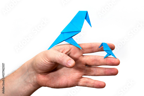 Hand holds an Origami bird made of colored paper isolated on white background