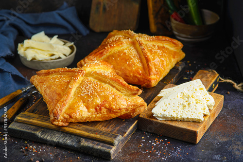 khachapuri with cheese served on wooden board near ingredients on dark background with scattered spices.
 photo