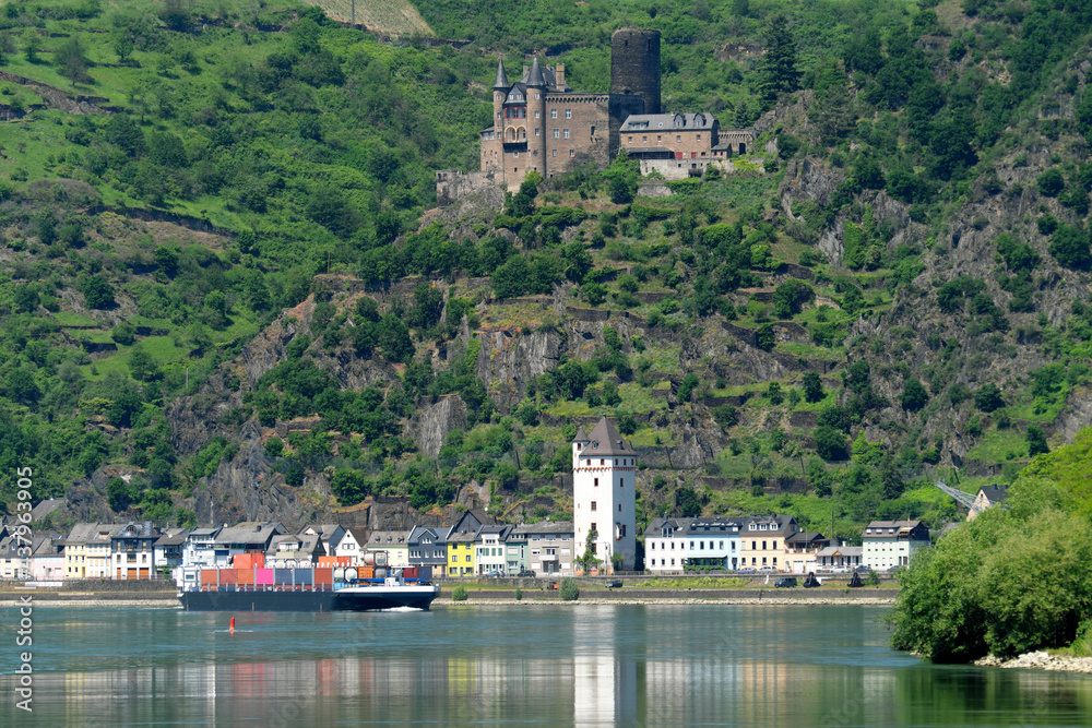 Containerschiff auf dem Rhein im oberen Mittelrheintal und Panorama von St. Goarshausen mit Burg Katz - Stockfoto