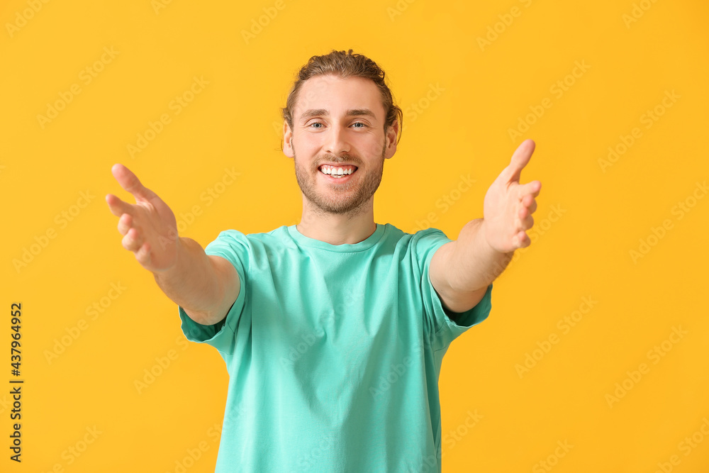 Fototapeta premium Handsome man opening arms for hug on color background