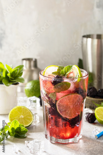 Summer blackberry mojito or blackberry soda. Refreshing summer drink with blackberry, mint, lime and ice on a stone table. Copy space.