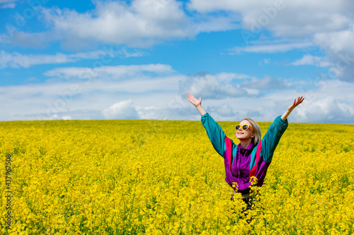 Beautiful woman in vintage tracksuit in yellow rapeseed field