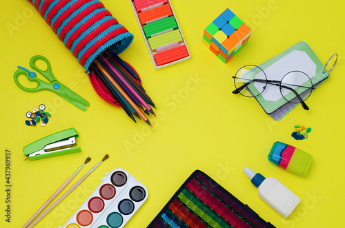 Back to school. School supplies: scissors, stationery buttons, stapler, brushes, paints, notebook, glue, grater, glasses,Rubik's cube, notebook,pencil case, bookmarks, pencils,plasticine.Bright colors