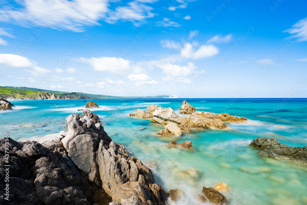 (Long exposure) Stunning view of a rocky coastline bathed by a turquoise, clear sea during a sunny, summer day, Rena Majore, Sardinia, Italy.
