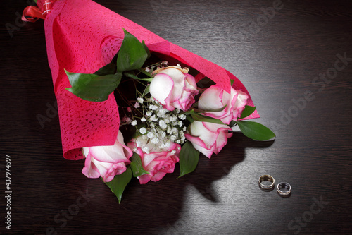 Bouquet of roses in a package of red paper and wedding rings