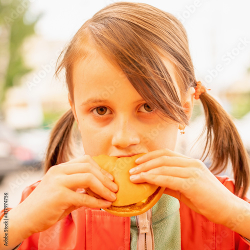 Portrait of young beautiful girl eating beef burger sandwich. Fast food concept.  Close up portrait.