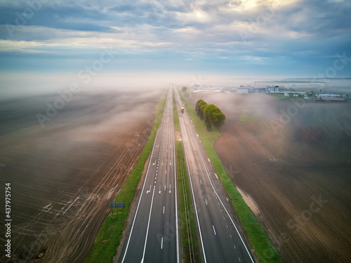 Obraz na płótnie Aerial view of a highway covered by fog. Early misty morning. Road in rainy spring summer fields. w salonie
