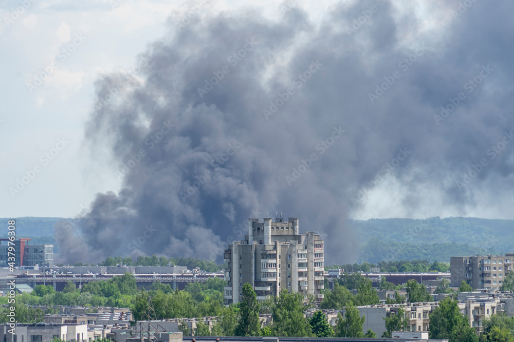 Fire in the city. Black column of smoke rises to the sky over city buildings Fire in the city. Black column of smoke rises to the sky over city buildings