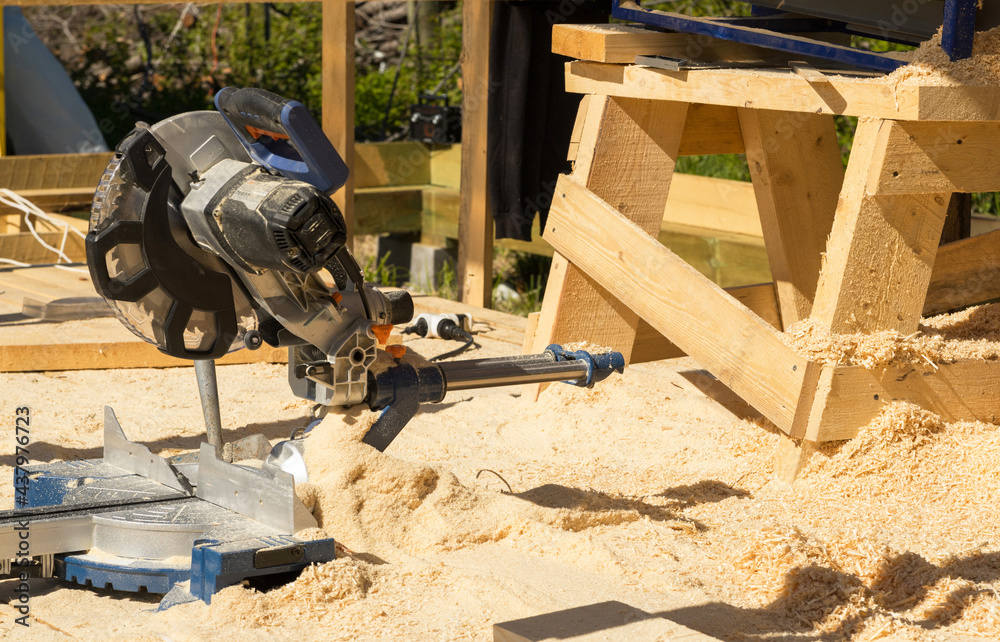 High-speed cutting circular saw.  The machine cuts off a piece of board on the street. Pruning a tree. Close up. a tool for construction. Building a house. Soft focus.