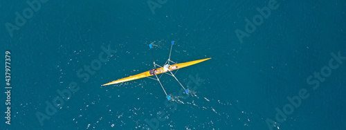 Aerial drone ultra wide photo of fit women athletes rowing in sport canoe in deep blue Aegean sea, Greece
