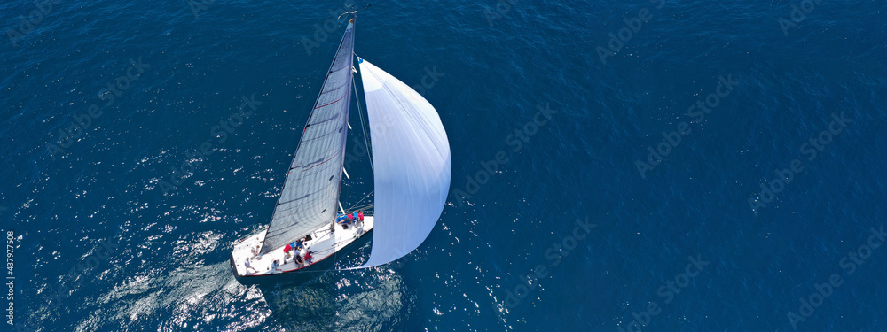 Aerial drone ultra wide panoramic photo of beautiful sail boat with white sails cruising deep blue sea near Mediterranean destination port
