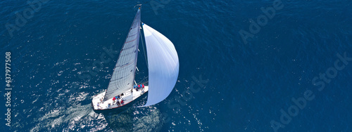 Obraz na płótnie Aerial drone ultra wide panoramic photo of beautiful sail boat with white sails cruising deep blue sea near Mediterranean destination port w salonie