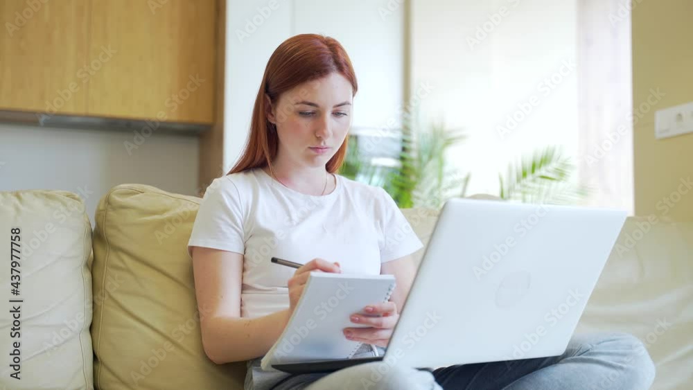 student girl studying online at home. Internet. e-learning with laptop video tutorials. Young woman on a sofa indoors notes in a notebook and teaches. Distance education. learning house on the couch student girl studying online at home. Internet. e-learning with laptop video tutorials. Young woman on a sofa indoors notes in a notebook and teaches. Distance education. learning house on the couch