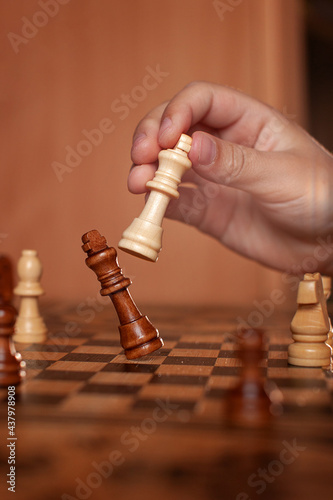 hand holds white king chess piece and hits drops black king chess piece chessboard. concept victory