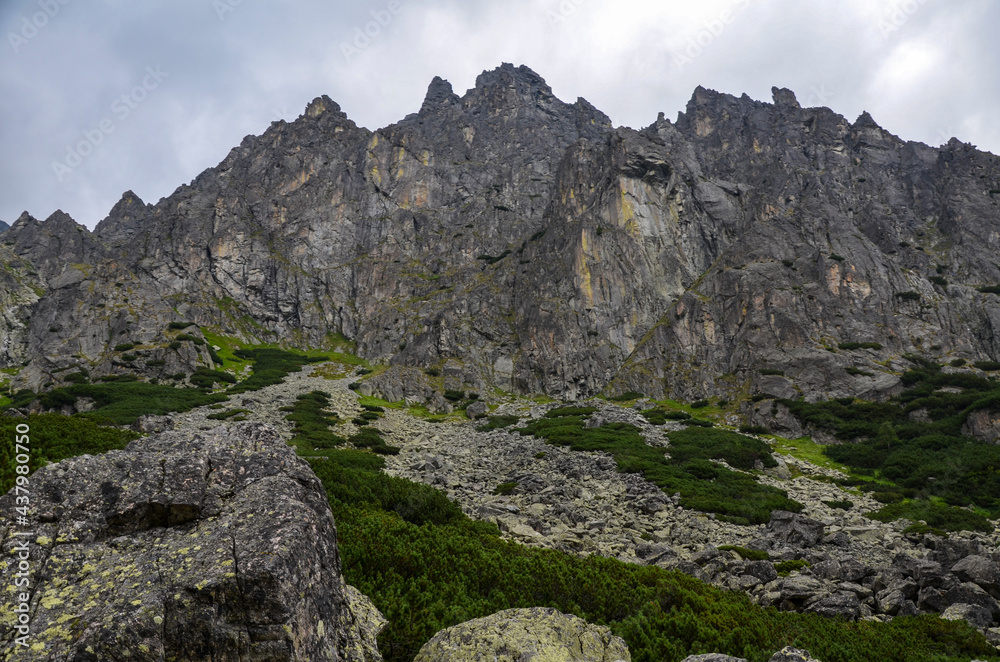 Landscape with high stone sharp rocky peaks under cloudy sky in National Park High Tatras Mountains, Slovakia. Tourist destination for hiking and tourism