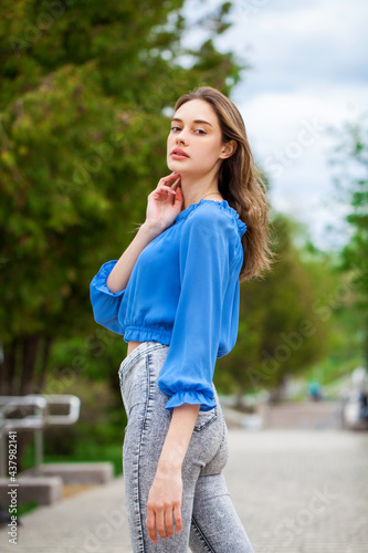 Young beautiful girl in a blue blouse and gray jeans © Andrey_Arkusha