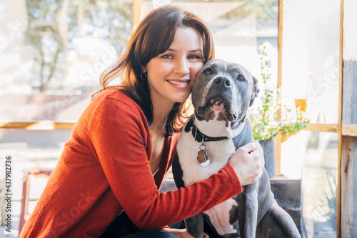 Smiling woman hugging her pet Pitbull dog photo