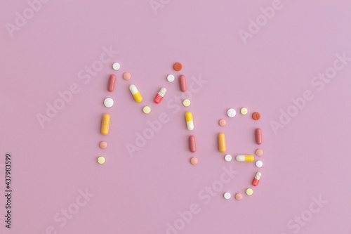 Magnesium symbol made from pills on purple background. Top view with copy space. Flat lay.