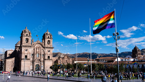 Bandera del tahuantinsuyo en la plaza de armas de Cusco, Perú con la iglesia de la compañia de Jesus de fondo. 