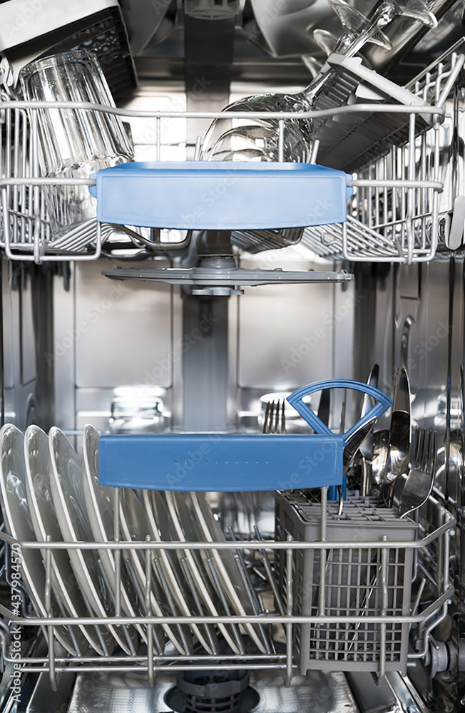 Vertical banner of a dishwasher tray with clean dishes, plates and cutlery, and glasses. Vertical banner of a dishwasher tray with clean dishes, plates and cutlery, and glasses.