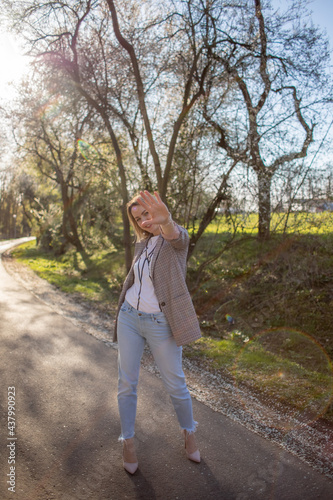 Beautiful funny girl in jacket stands on the road.