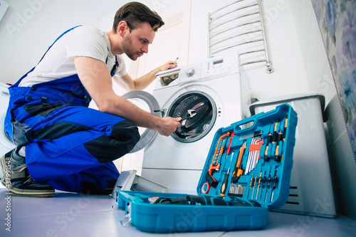 Bilde på lerret The young handsome repairman in worker suit with the professional tools box is f