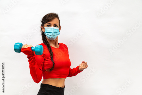 mulher malhando e fazendo exercícios físicos de mascara de proteção com pesos e halteres na mão, no fundo branco photo