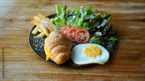Vegetarian croissant with cheese and porched egg with french fries and vegetable. Healthy European breakfast