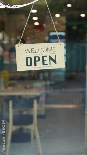 Open and closed flip sign in front of coffee shop and restaurant glass door. Wooden sign with wording of place's status. Say sorry we're closed. Please come back again and another side.