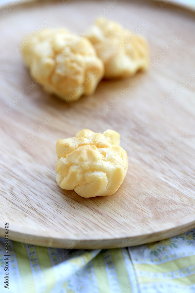 Choux cream, small fluffy creamy yummy vanilla inserted in round dessert as cold fresh sweet on wood plate. Choux cream, small fluffy creamy yummy vanilla inserted in round dessert as cold fresh sweet on wood plate.