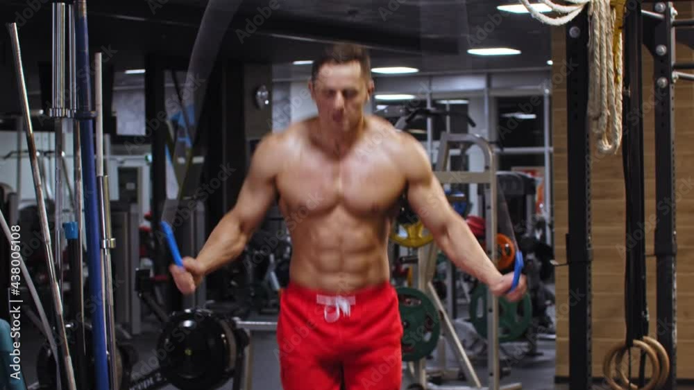 Adult pumped up man doing rope exercise in the gym at night Adult pumped up man doing rope exercise in the gym at night