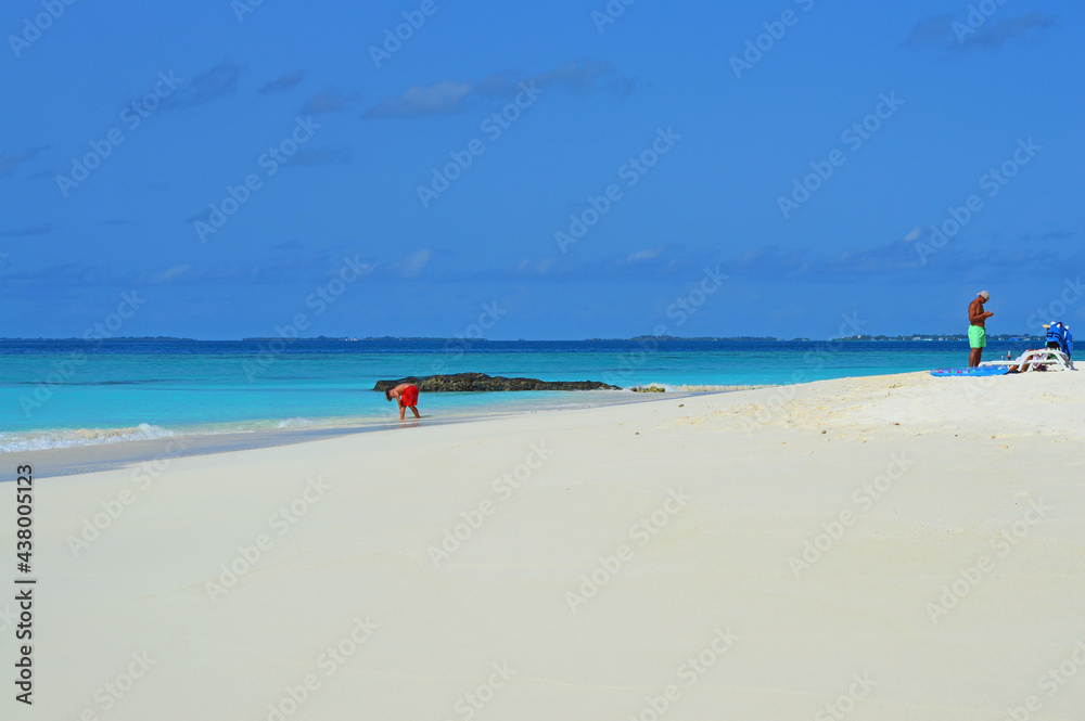 A boy and his father spend times on sand beach in Maldives