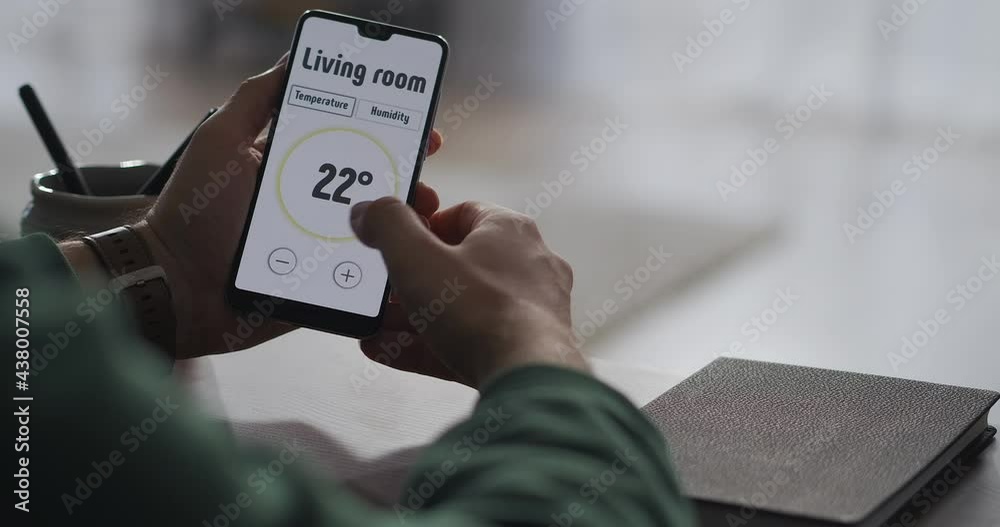 man is using modern app in smartphone for controlling parameters of smart home system, closeup view of screen