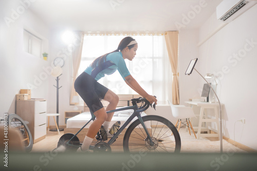 Asian woman Riding a bike online trainer in the bedroom