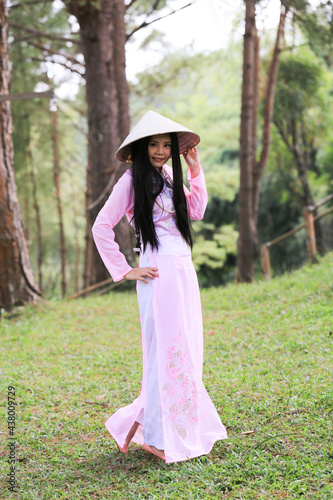Asian woman, VIetnamese woman in Ao Dai, traditonal ancient female costume with straw hat. Long sleeves and long dress with white pant