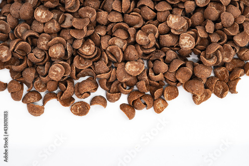 Background with chocolate cereals on white. top view of a large group with many chocolate flavored corn flakes. Cacao. Cocoa. Breakfast. Delicious. Crunchy. Cereal