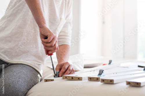 Woman using screwdriver to assemble furniture