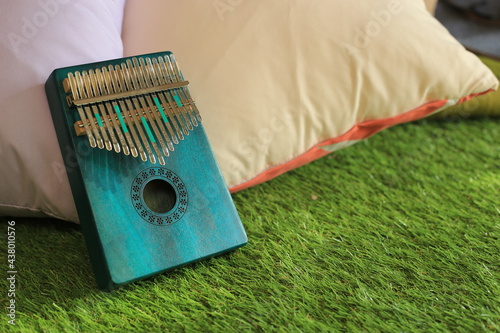 Kalimba or mbira is an African musical instrument.Traditional small Kalimba made from  wooden board with metal, play on  hands and plucking the tines with the thumbs. Instrument in room photo