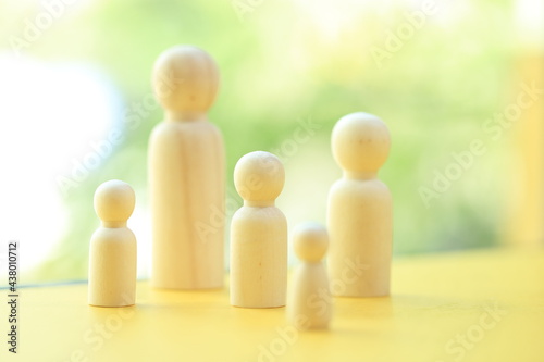 Family group of wood doll as mother, father and kids as represent human relationship in cousin with green bokeh as background.